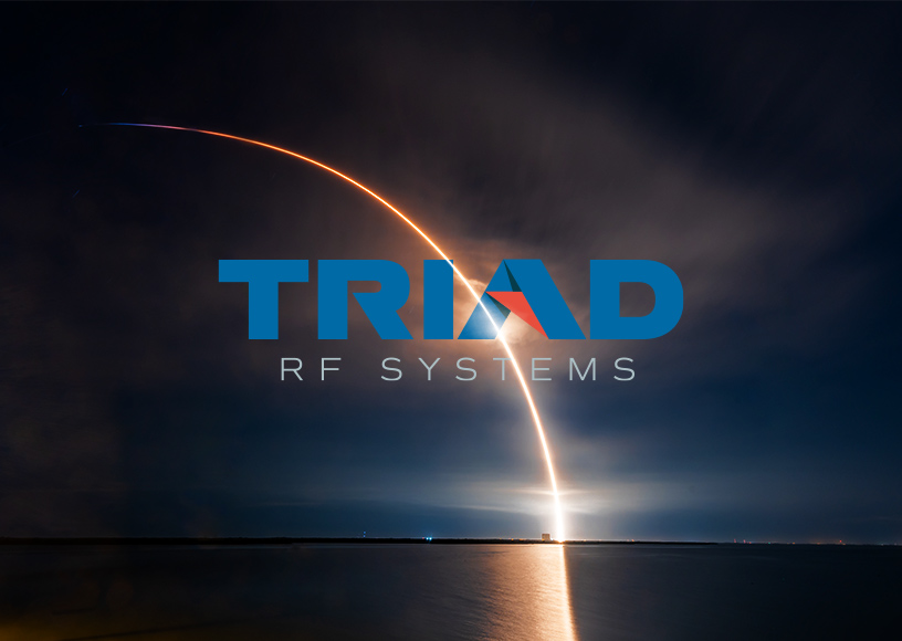 The Triad Logo imposed on a view of the horizon over the sea at night with a rocket launching.